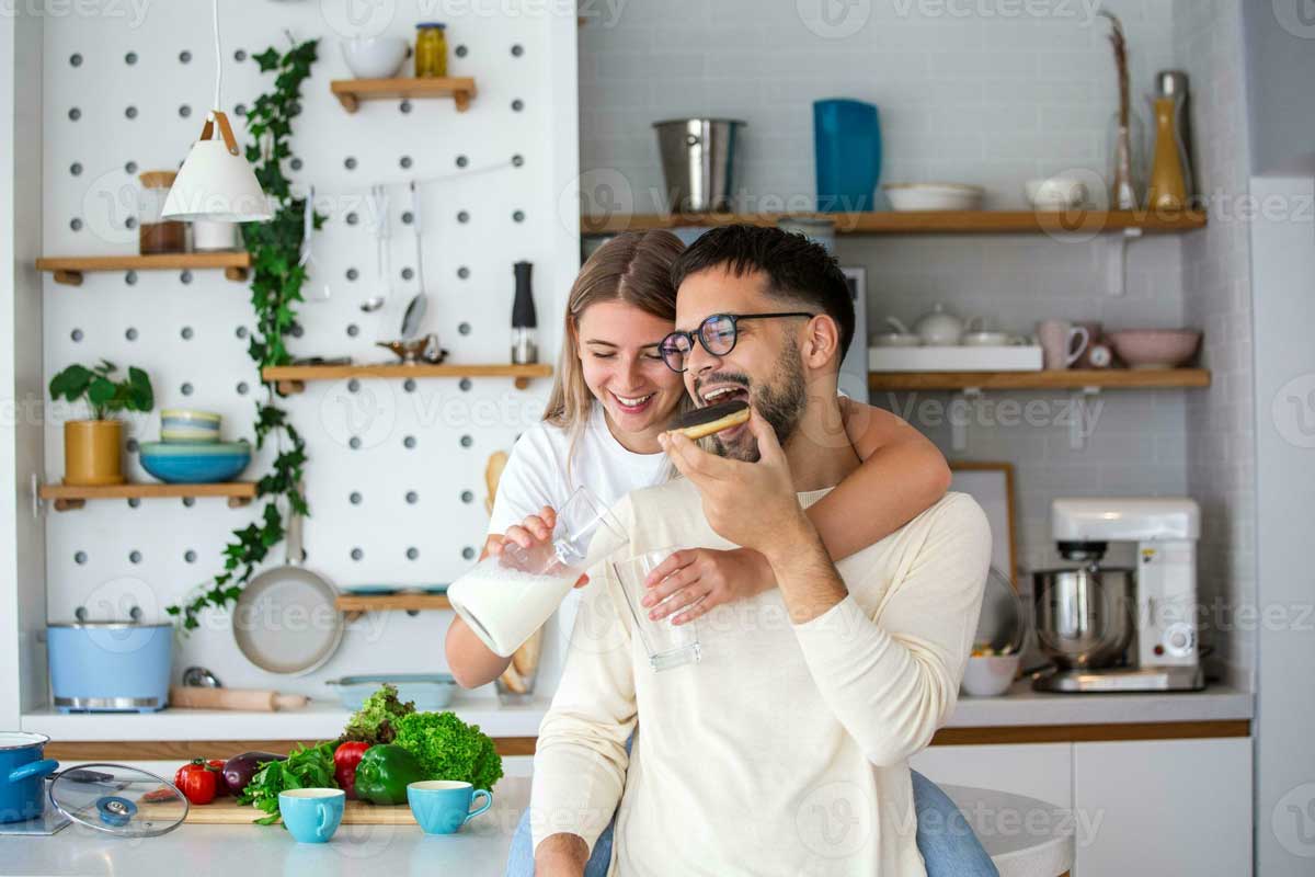 portrait-of-happy-young-couple-cooking-together-in-the-kitchen-at-home-cute-young-couple-enjoying-their-breakfast-together-she-is-pouring-him-milk-photo